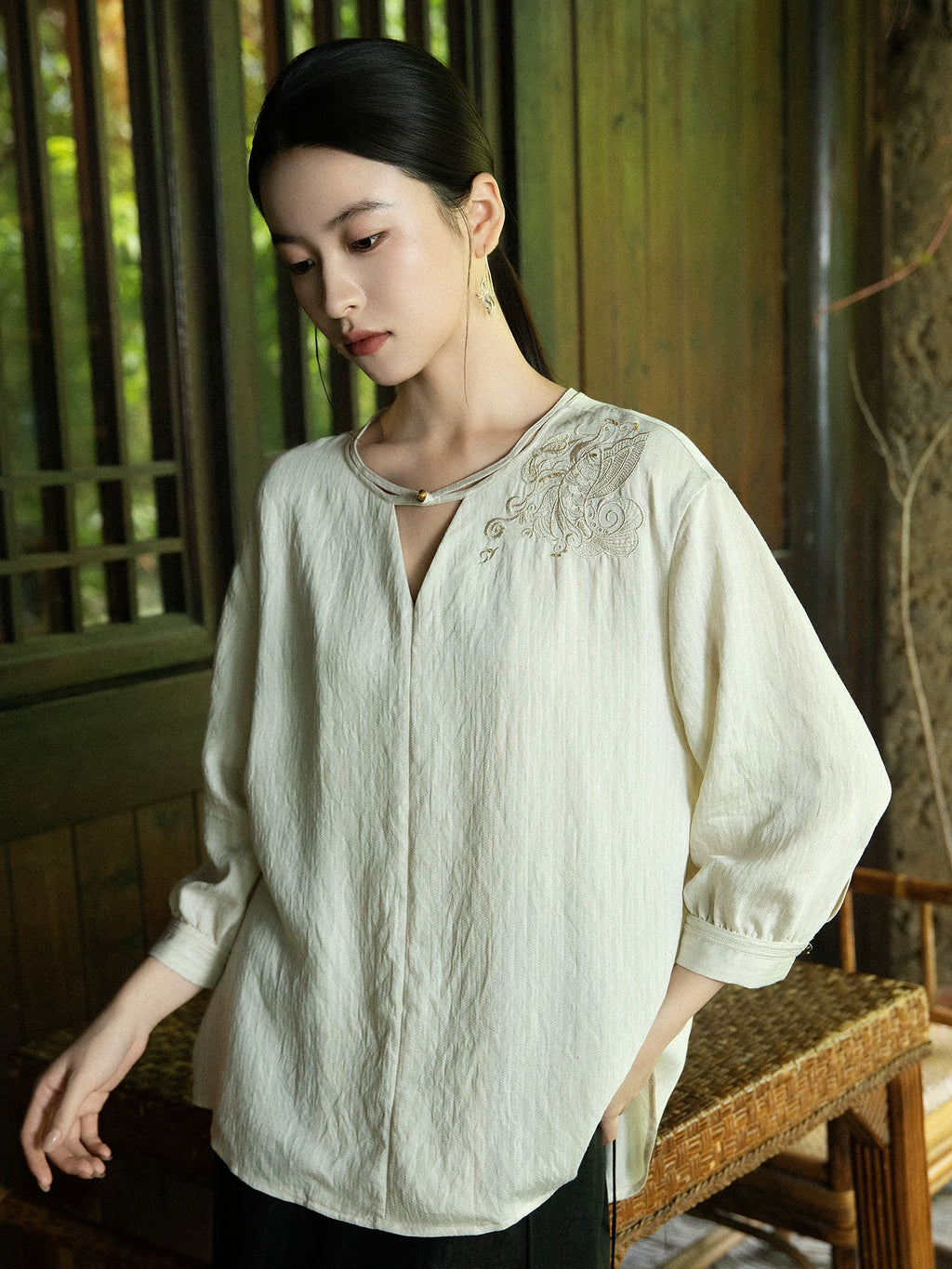 Women's embroidered casual blouse photographed in a traditional wooden interior.