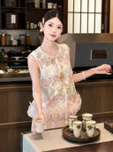 Model wearing a white sleeveless Cheongsam vest with pink floral embroidery, sequins, and a ruffled hem, holding a tea cup, crafted from 100% polyester.
