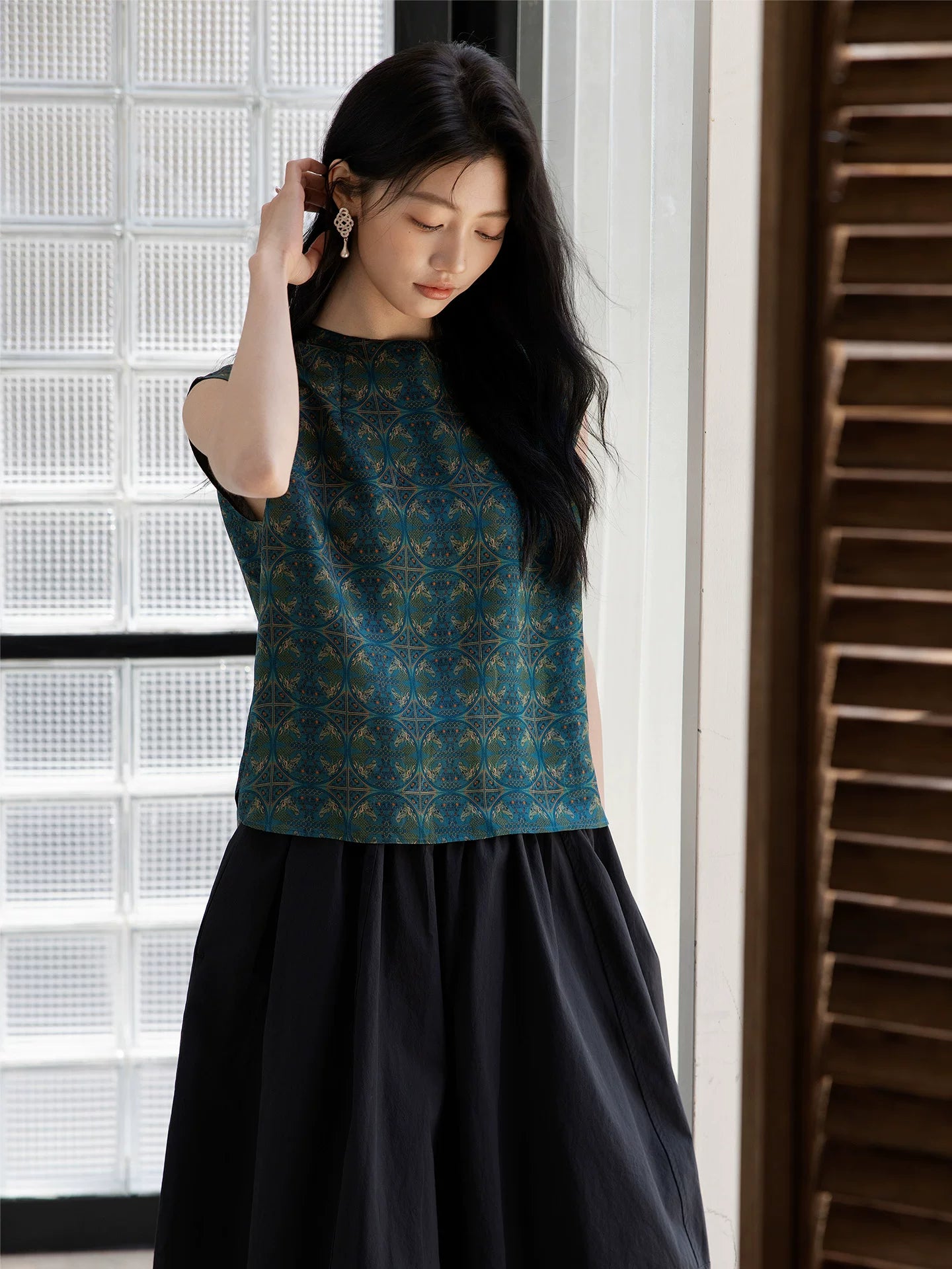 Close-up of an emerald mulberry silk blouse showing the geometric woven pattern.