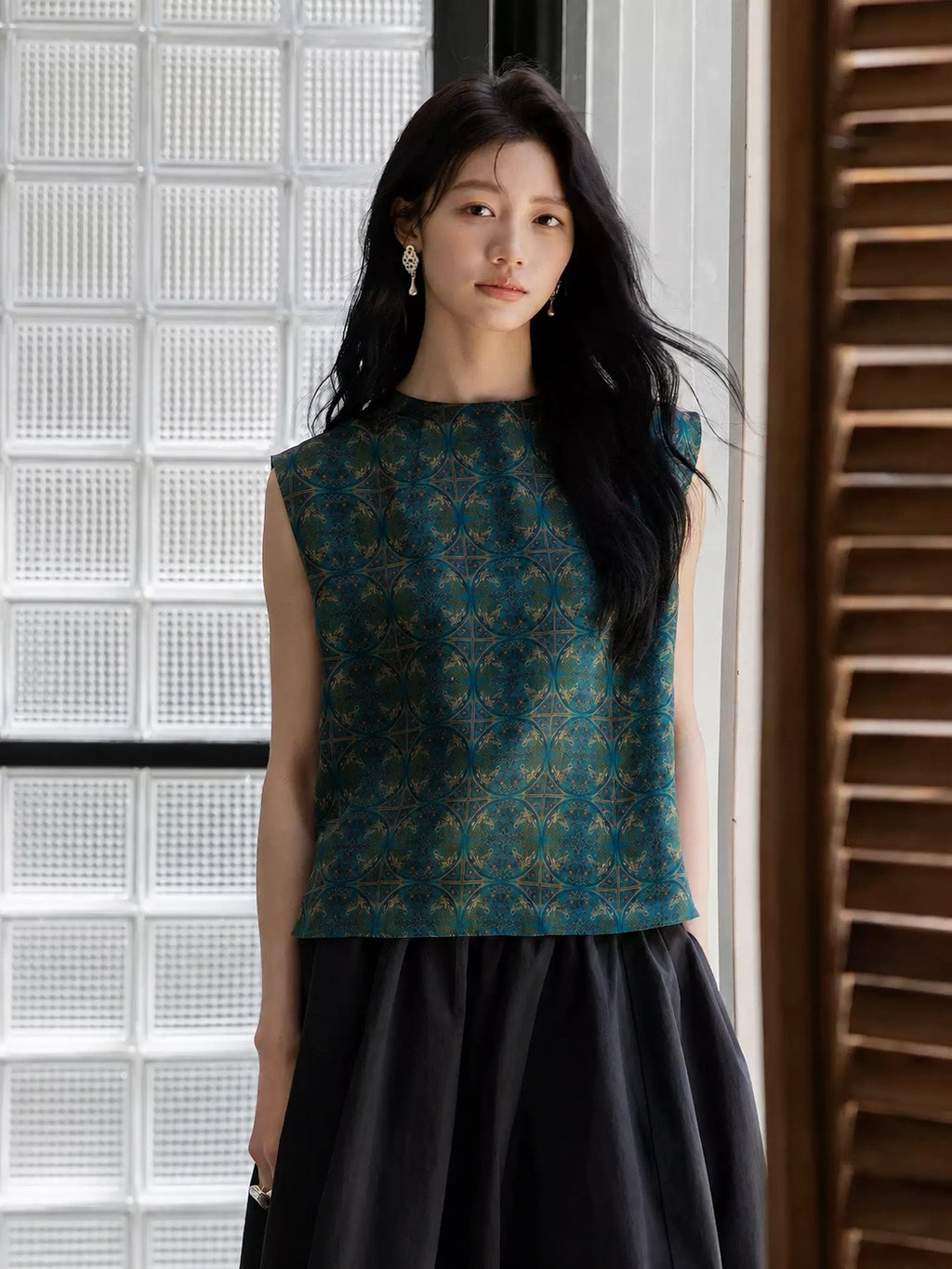Woman wearing an emerald sleeveless mulberry silk blouse with a black skirt.