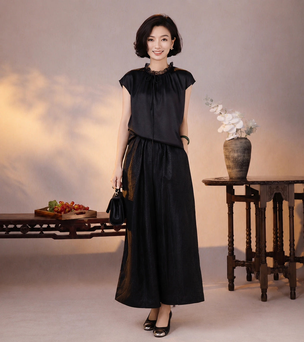 French-inspired black silk blouse styled with tonal wide-leg pants and a small black handbag