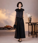 French-inspired black silk blouse styled with tonal wide-leg pants and a small black handbag