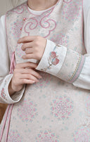 Close-up of the white inner top’s embroidered cuff beside the pink jacquard vest.