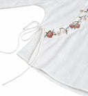 Close-up of the botanical embroidery, side tie and white jacquard fabric