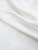 Close-up of the white fabric’s subtle floral and butterfly jacquard pattern
