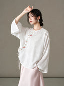 Model wearing the blouse with one arm raised, showing the drape of its wide sleeve