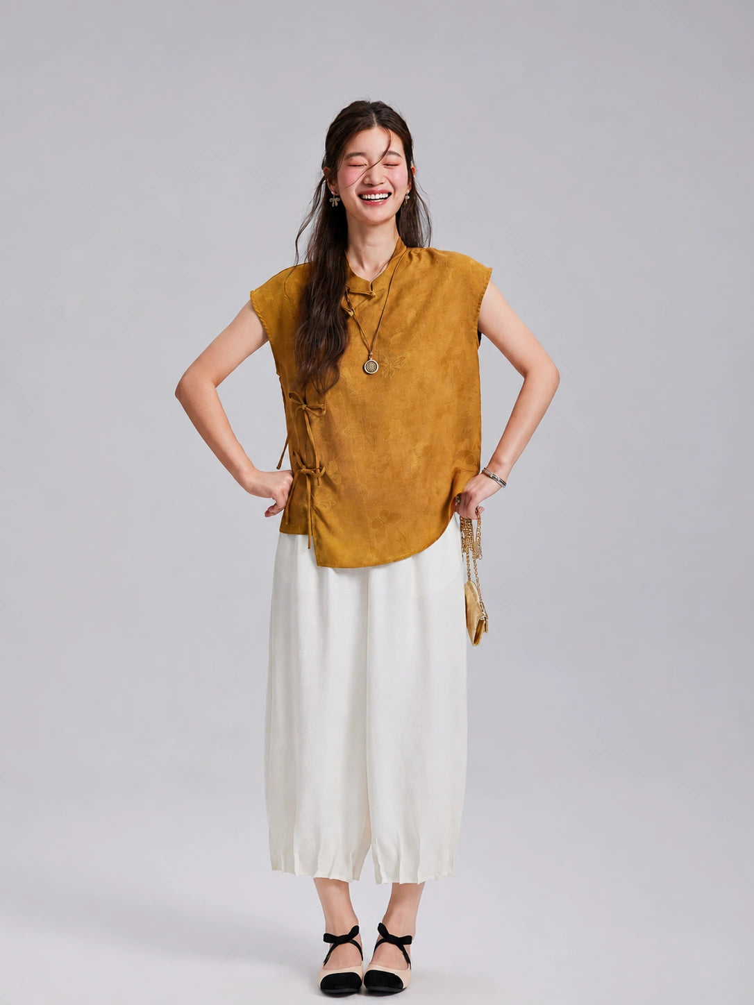 Model wearing an antique-gold Gambiered Silk jacquard top with ivory wide-leg trousers.