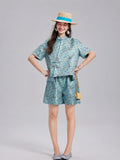 Model wearing an aqua Shu brocade short-sleeve shirt and coordinating silk shorts.