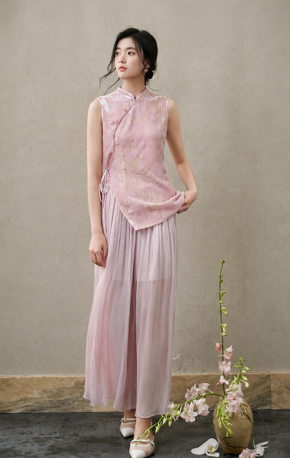 Front view of a fitted blush-pink cut-velvet vest with asymmetric frog buttons and side ties