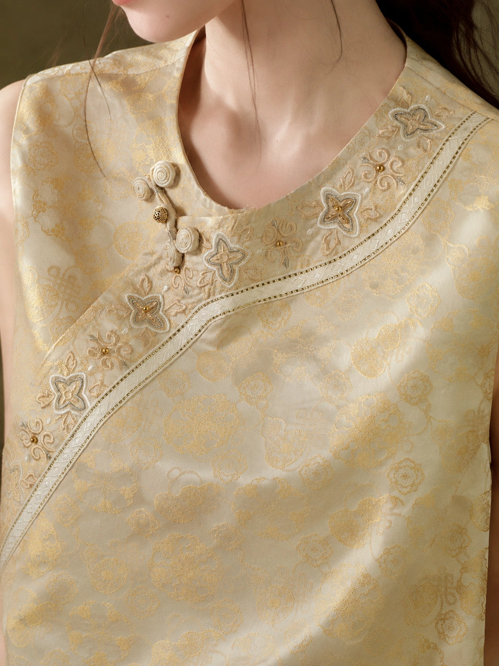 Close-up of the knotted buttons, floral appliqué, bead accents and curved embroidered neckline