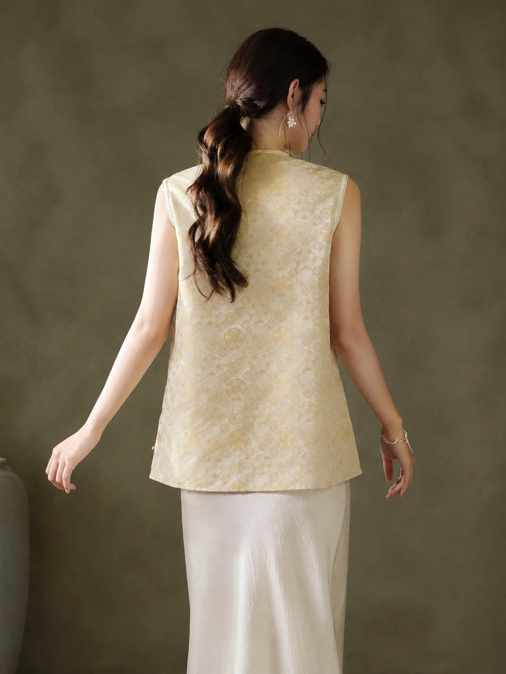 Back view of the relaxed sleeveless vest with an all-over gold Baoxiang floral pattern