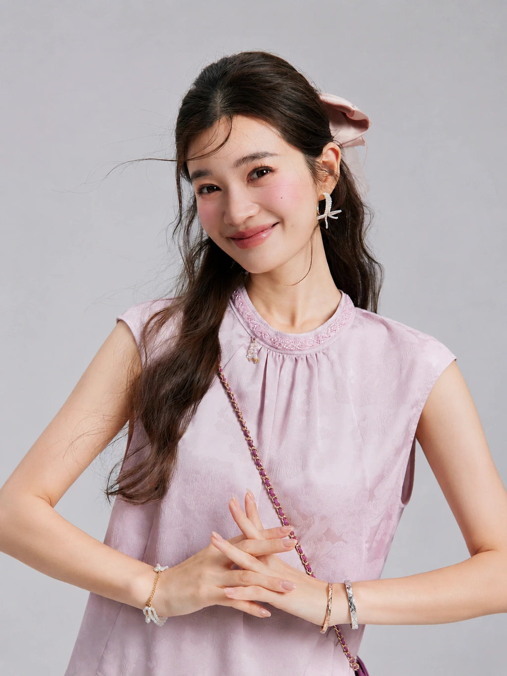Close view of the beaded round neckline and gathered front of a blush-lilac jacquard top.