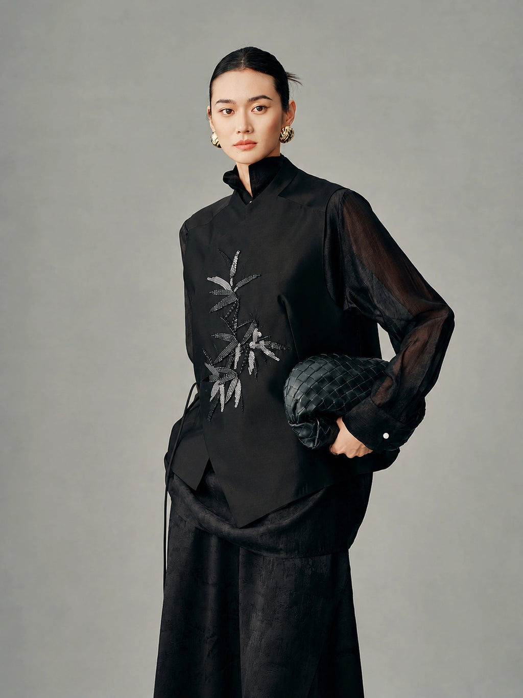 Model wearing the black wool-silk vest with beaded bamboo embroidery and an asymmetric wrap front