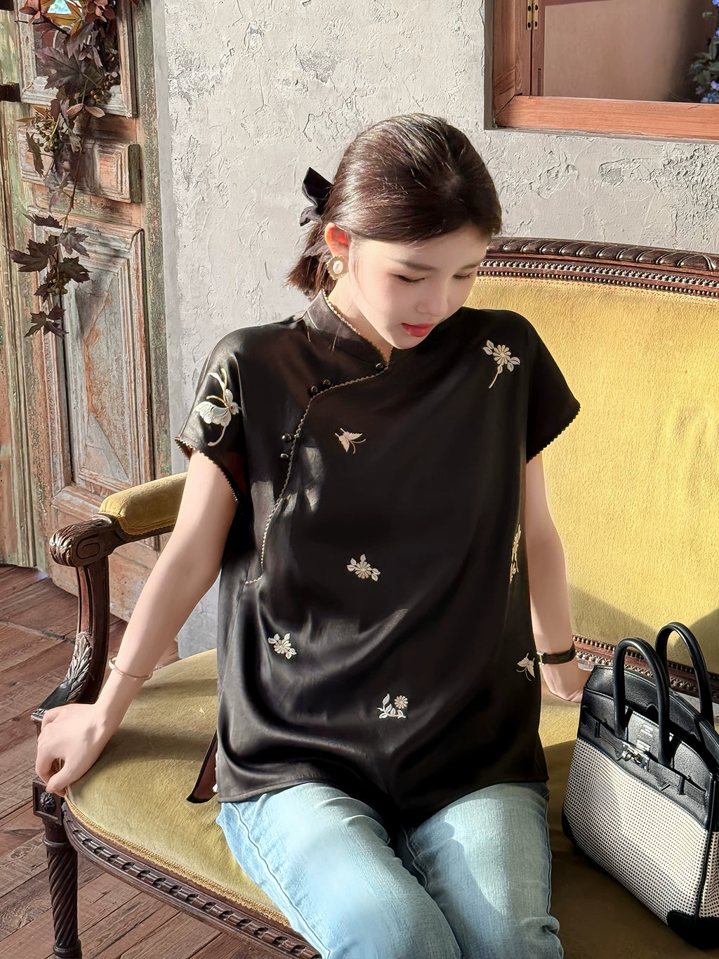Model wearing a black Chinese-inspired silk top with an asymmetrical front closure