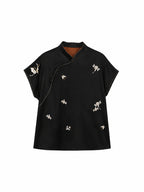 Front view of a black mulberry silk top with floral embroidery and pink piping