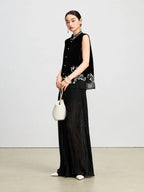 Three-quarter view of a jet-black velvet vest featuring ivory botanical embroidery and pearl-style buttons.
