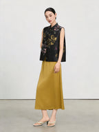 Model wearing a black hand-painted floral silk vest with a mustard yellow maxi skirt.