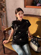 Model styling a black embroidered silk top with short flutter sleeves