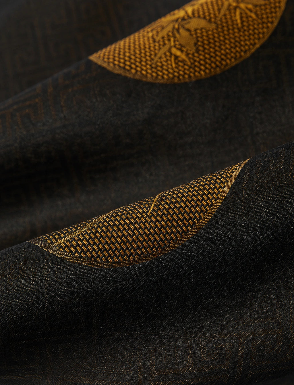 Macro view of the espresso-black jacquard fabric with antique-gold woven botanical detailing.