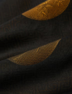 Macro view of the espresso-black jacquard fabric with antique-gold woven botanical detailing.