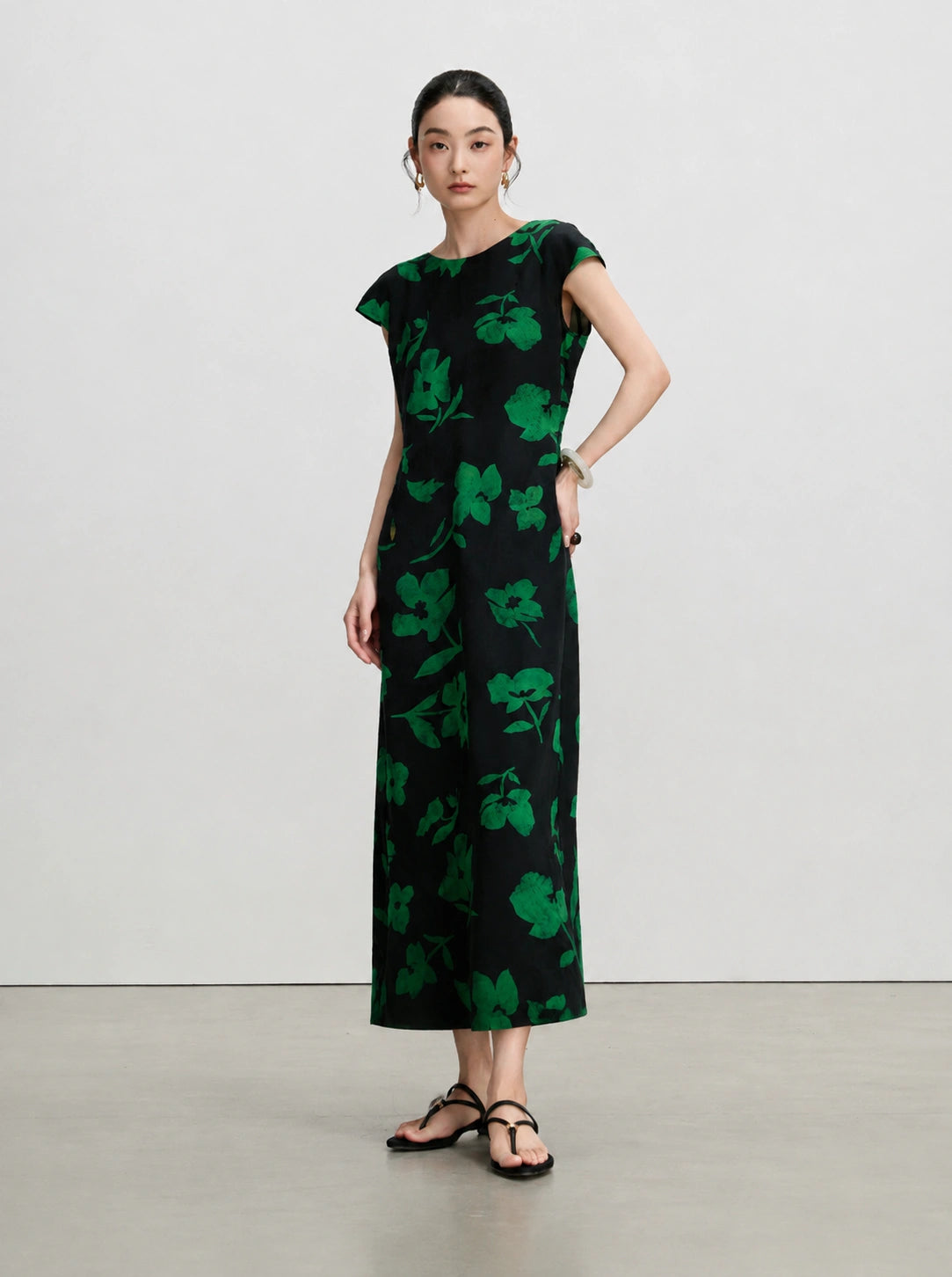 Side view of a slim-fitting black silk maxi dress with green floral print and cap sleeves.