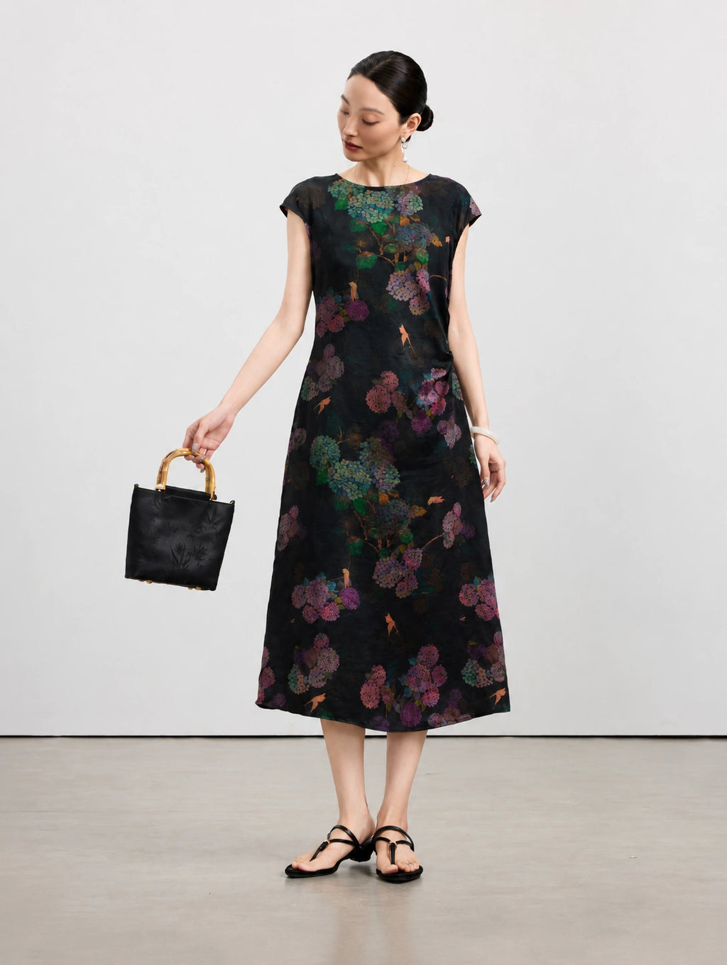 Woman wearing a black 100% mulberry silk midi dress with colorful hydrangea flowers.