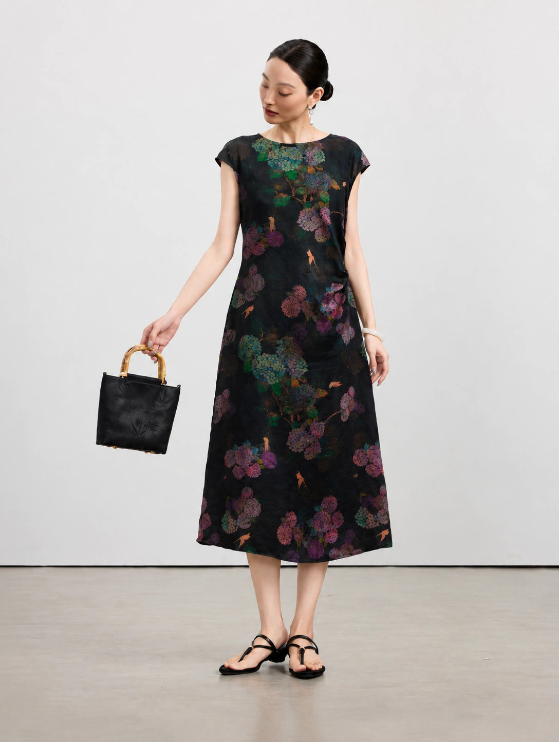 Woman wearing a black 100% mulberry silk midi dress with colorful hydrangea flowers.