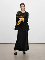 Close-up of the round neckline, covered button and tortoiseshell-inspired texture of the black silk jacket.
