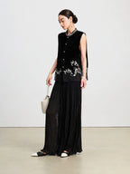 Model styling a black sleeveless silk vest with an embroidered Mandarin collar and floral hem.