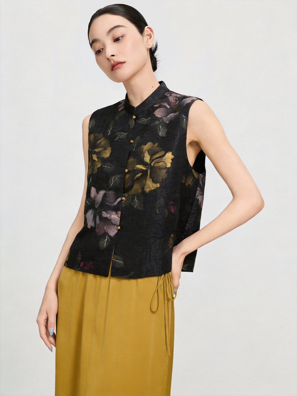 Detailed view of the hand-painted floral pattern and gold-tone button closure on the black silk vest.