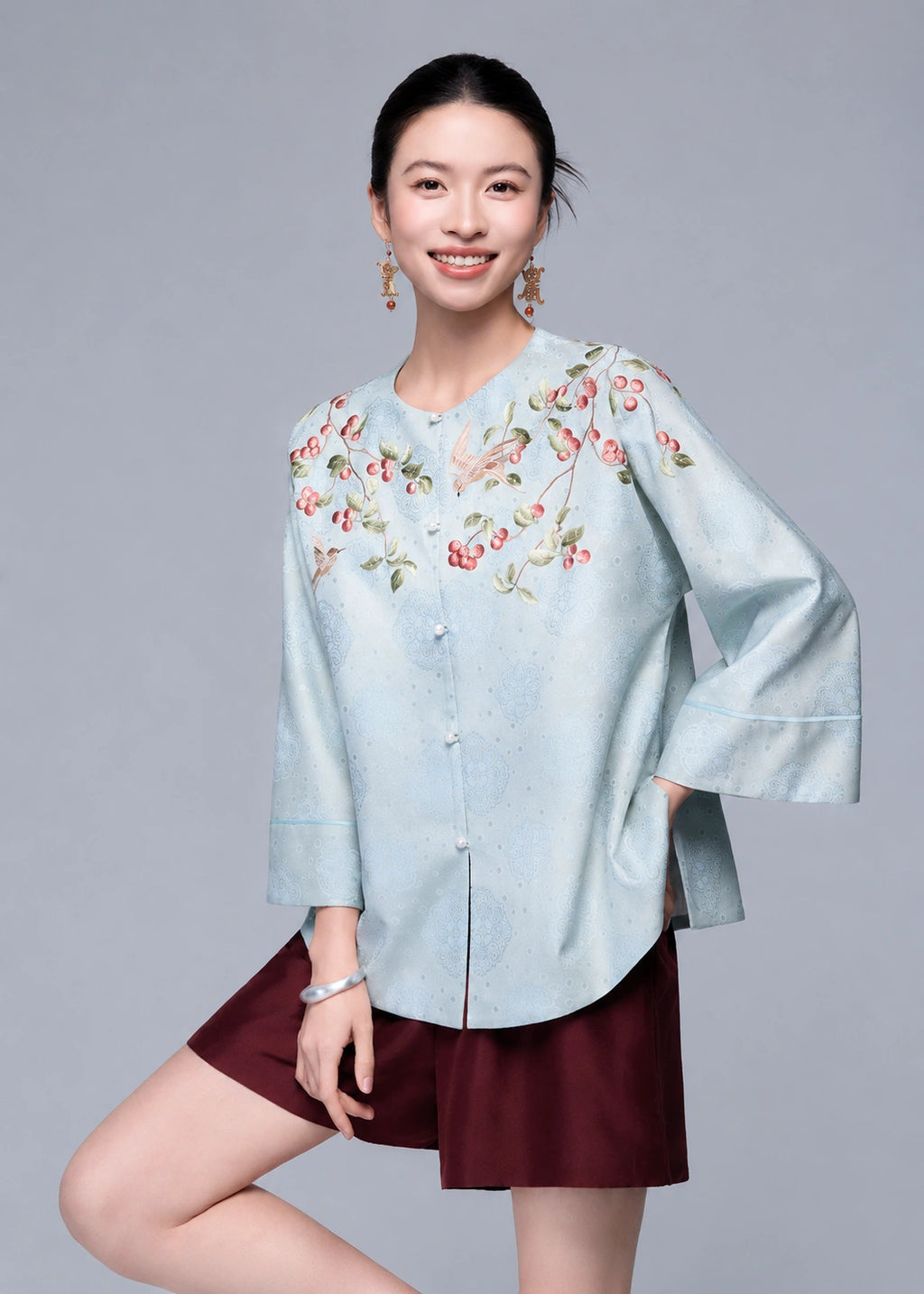 Closer front view of the powder blue cardigan showing the berry and bird embroidery across the shoulders.