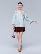 Front view of the powder blue silk-blend cardigan featuring botanical embroidery, wide sleeves and pearl-style buttons.
