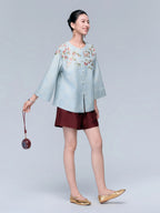 Model wearing the powder blue floral and bird leno silk cardigan with burgundy shorts, shown from a side angle.