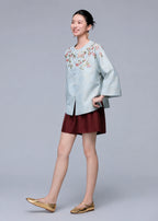 Three-quarter view of a model wearing the powder blue botanical silk-blend cardigan with relaxed wide sleeves.