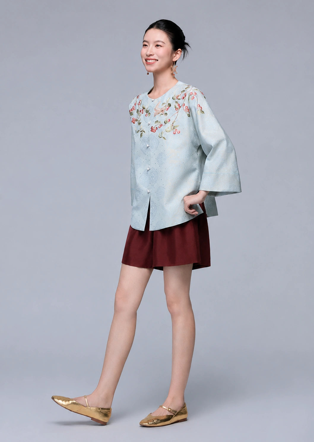 Three-quarter view of a model wearing the powder blue botanical silk-blend cardigan with relaxed wide sleeves.
