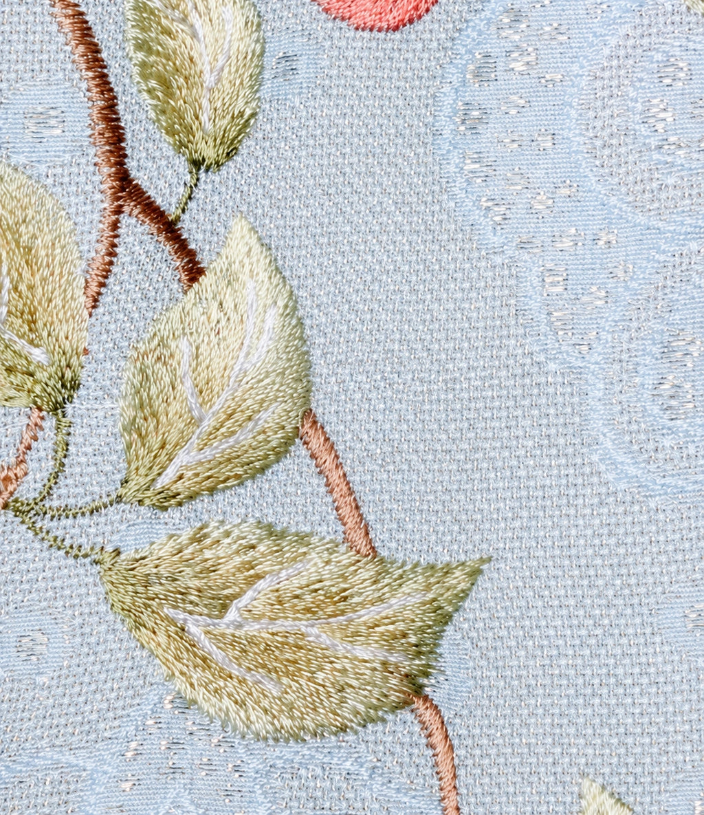 Close-up of the powder blue leno-weave fabric showing its open texture, subtle shimmer and embroidered leaves.