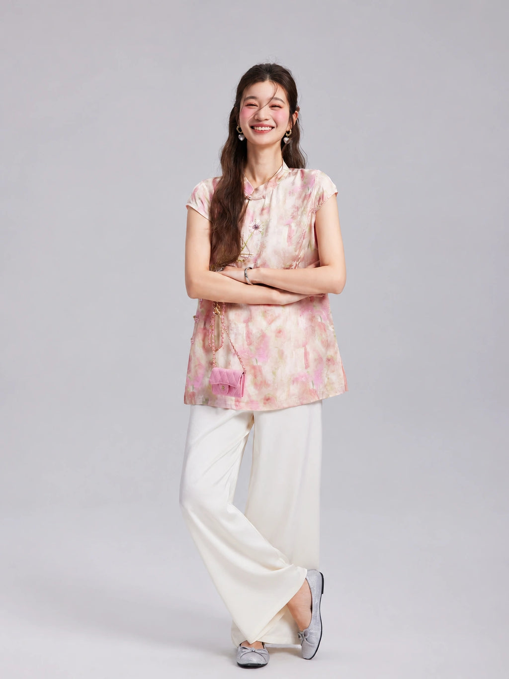 Model wearing a Gambiered Silk blush floral embroidered longline top with white wide-leg trousers