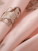 Close-up of lustrous blush pink mulberry silk fabric with woven pony motifs in brown and champagne tones