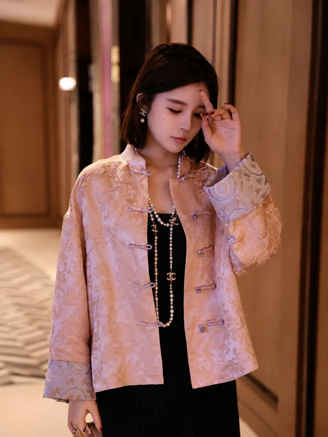 Model styling a blush pink silk-blend jacket with contrasting blue cuff details