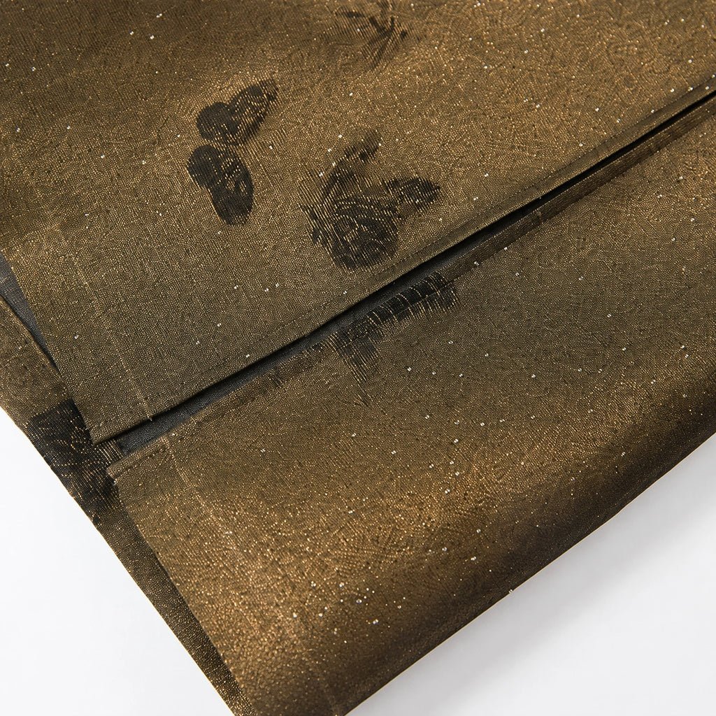 Close-up of the translucent silk-blend fabric with woven butterflies and fine sparkling accents