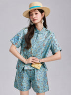 Model wearing a relaxed aqua butterfly-patterned silk shirt with matching wide-leg shorts.