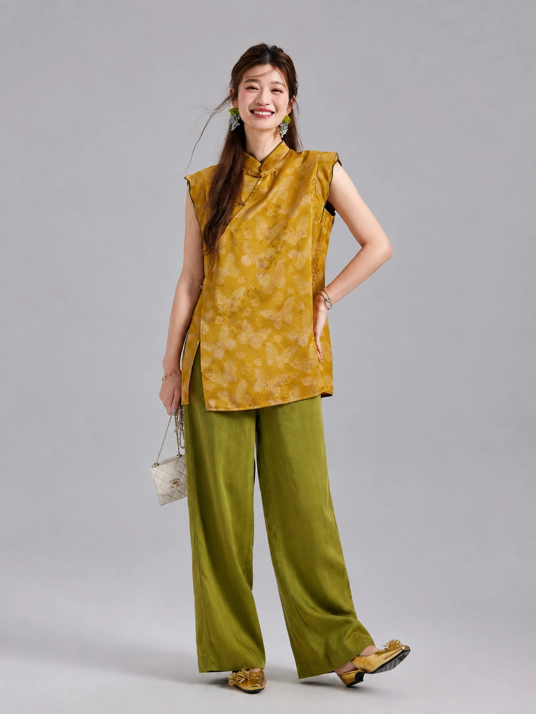 Model wearing a golden butterfly silk top by Gambiered Silk with olive green wide-leg trousers