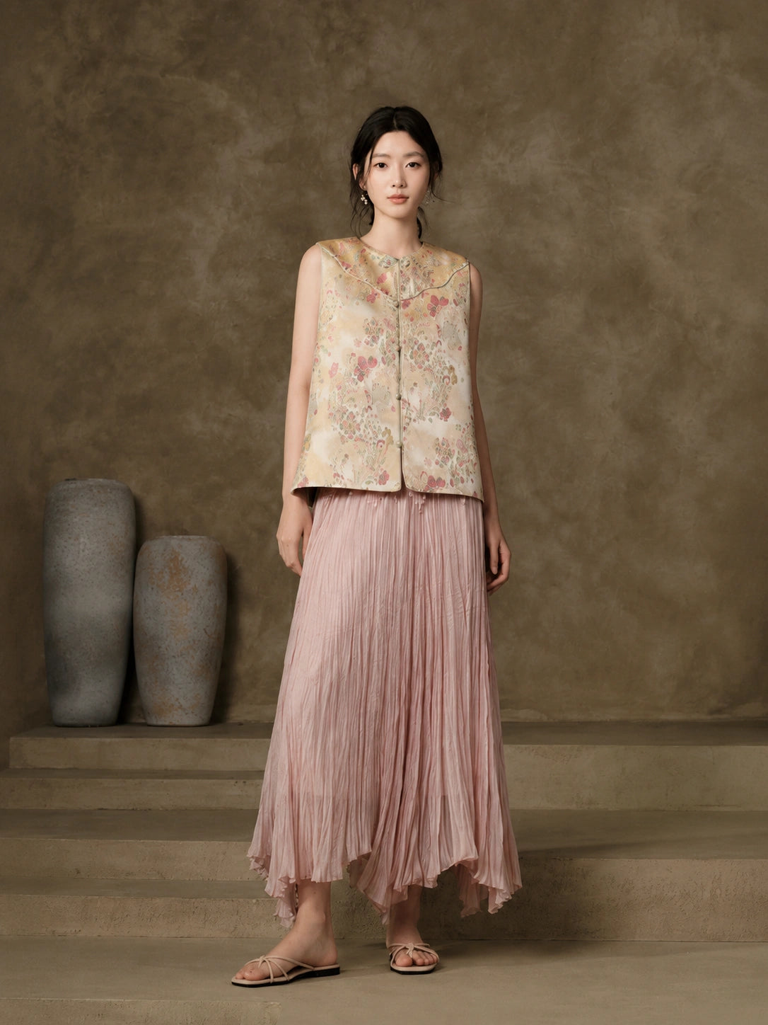 Front view of the champagne floral jacquard vest styled with a flowing pink skirt