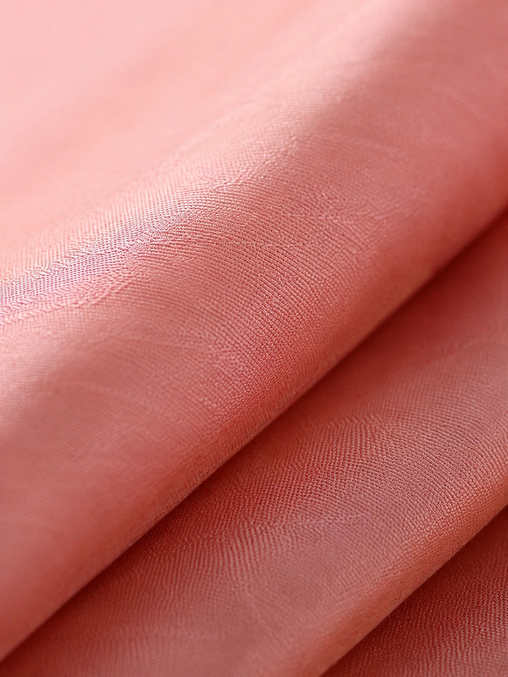 Close-up of lustrous coral pink mulberry silk fabric with a subtle tone-on-tone jacquard texture