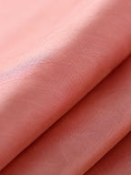 Close-up of lustrous coral pink mulberry silk fabric with a subtle tone-on-tone jacquard texture