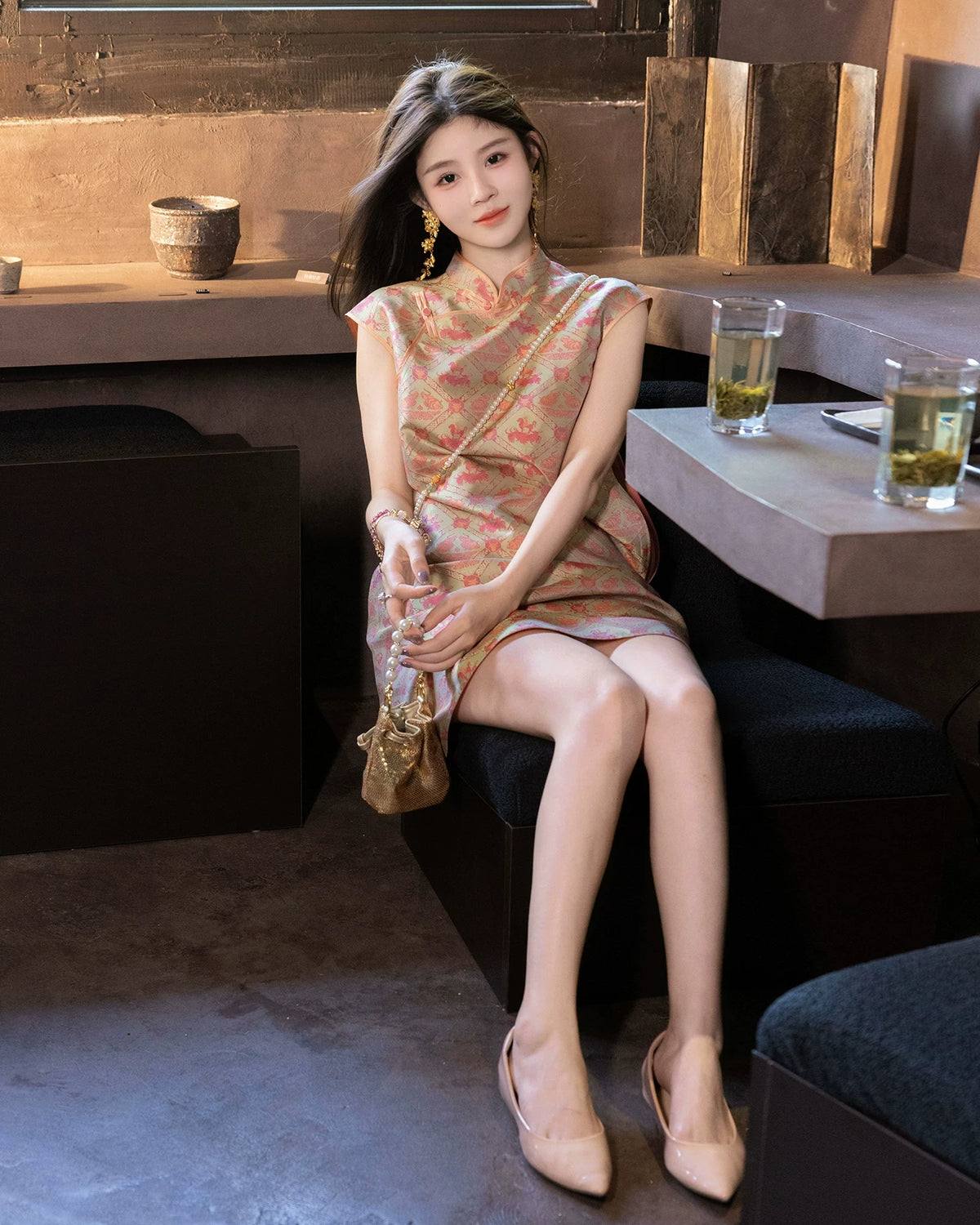 Lifestyle view of a model wearing a coral patterned mulberry silk dress with flutter cap sleeves.