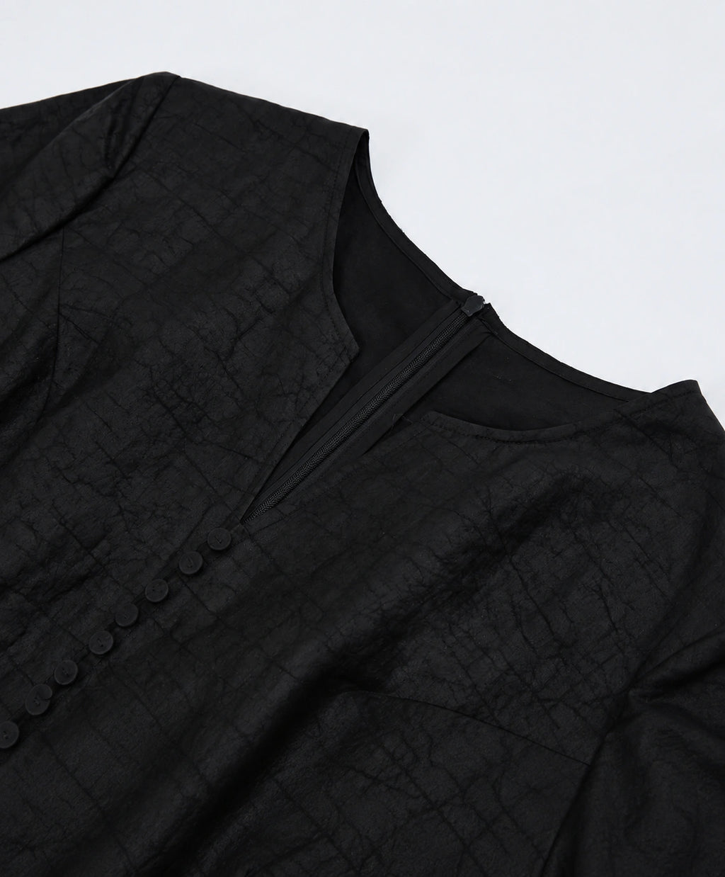 Close-up of the neckline construction, concealed zipper and tonal covered buttons
