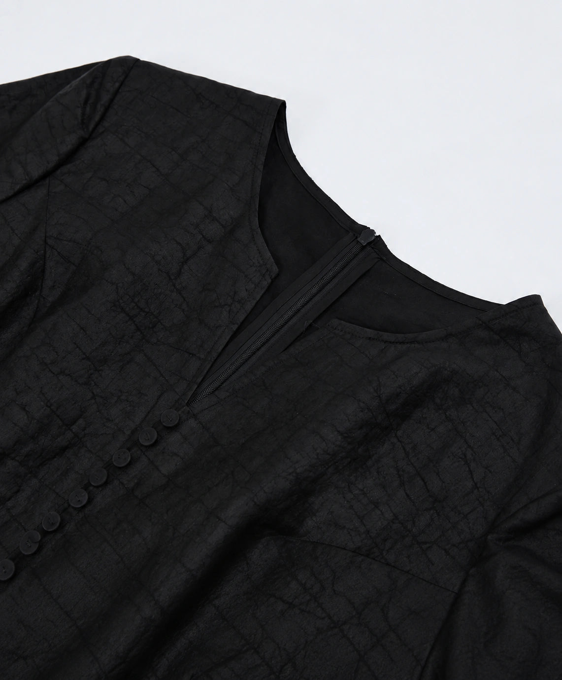 Close-up of the neckline construction, concealed zipper and tonal covered buttons
