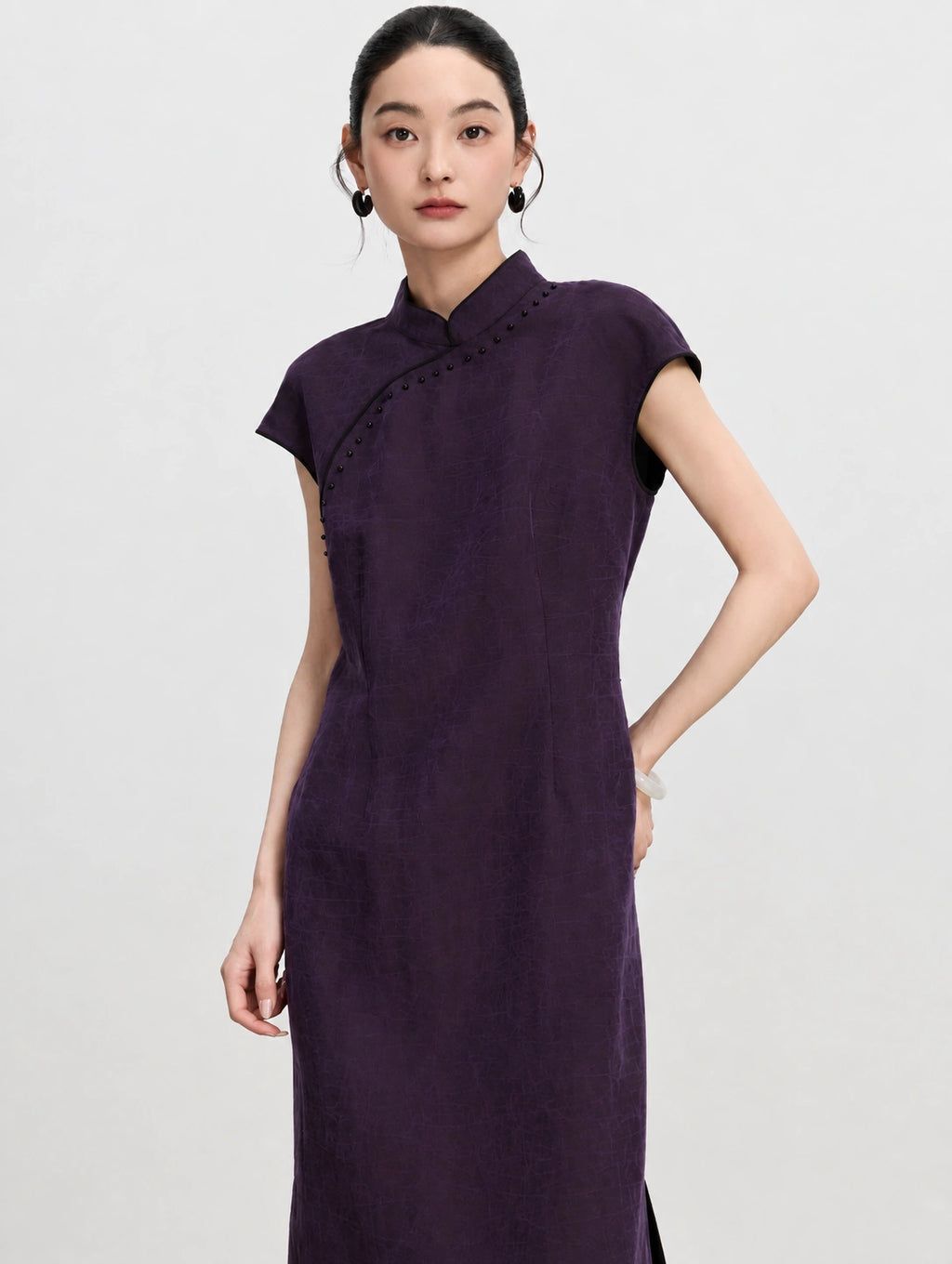 Three-quarter view showing the shaped waist and cap sleeves of a purple mulberry silk qipao dress.