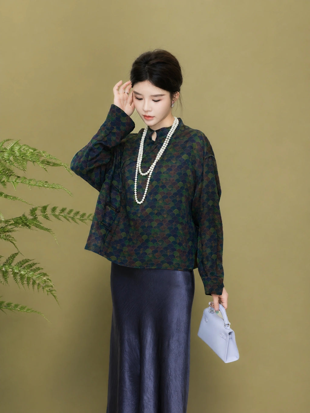 Model styling a relaxed dark green patterned silk jacket with a long skirt